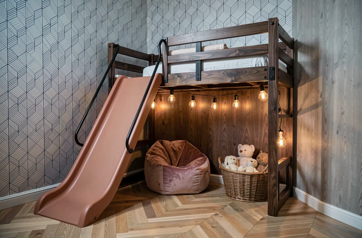 Coin lecture aménagé sous un lit cabane en bois foncé avec toboggan terracotta, guirlande lumineuse et pouf velours dans une chambre design